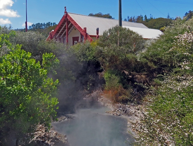 Hot steam rises from a geothermal spring beside a Maori house near Rotorua.