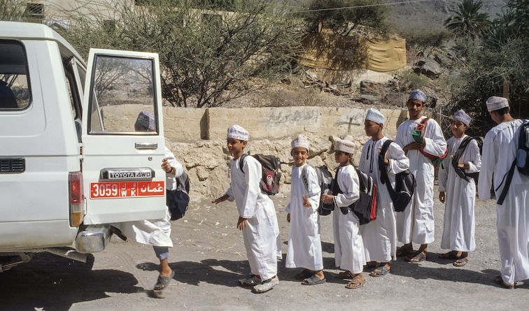 Omani schoolboys getting into school bus to return home. 