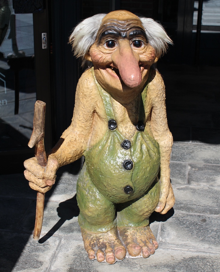 A wooden troll figurine outside a tourist trinket shop along the Bryggen waterfront.