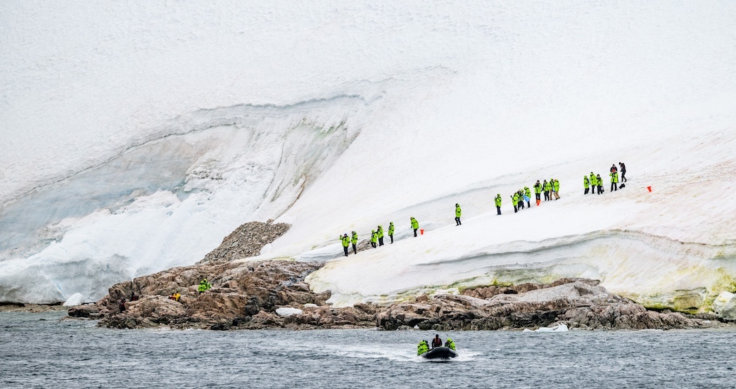 A zodiac full of guests returns to the ship after an excursion.